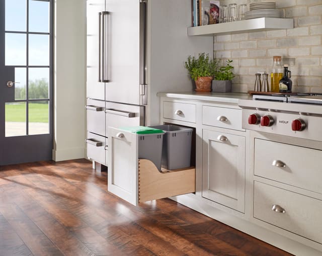 Double trash pull-out open in a white farmhouse kitchen