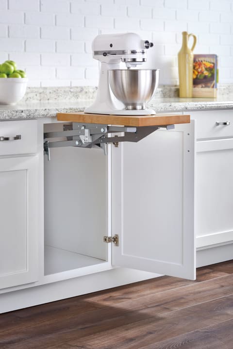 Stand mixer raised up to counter height on a mixer lift shelf that swings out of a white base cabinet