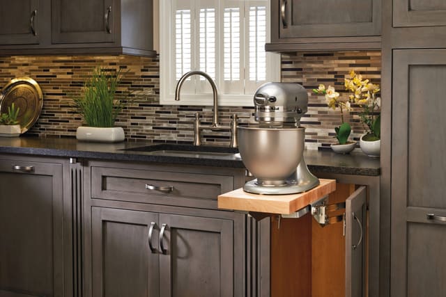 Mixer lift holding a stand mixer at counter height in a dark wood kitchen