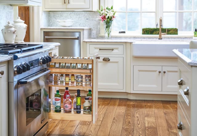 Narrow spice pull-out open next to the range in a bright white kitchen