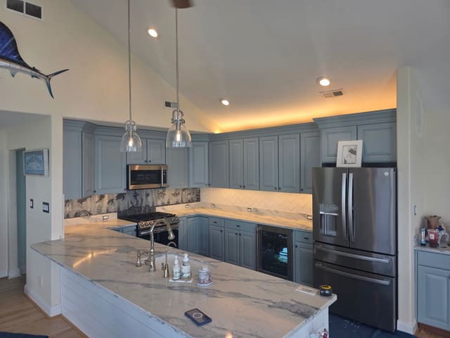 Finished Somers Point kitchen with blue cabinets, Liraz quartz countertops and a laser-etched seascape backsplash